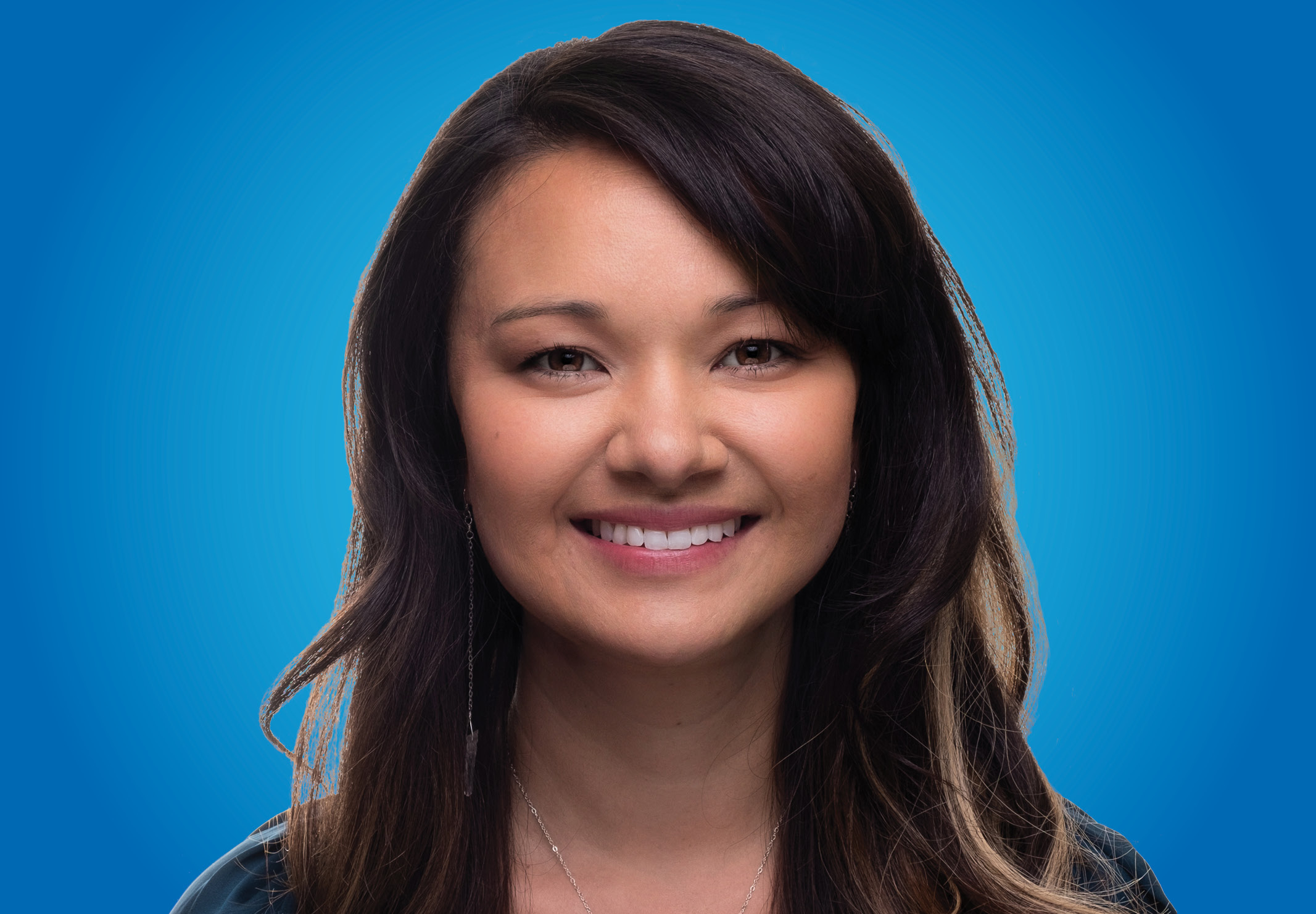 young woman with long highlighted hair against blue background