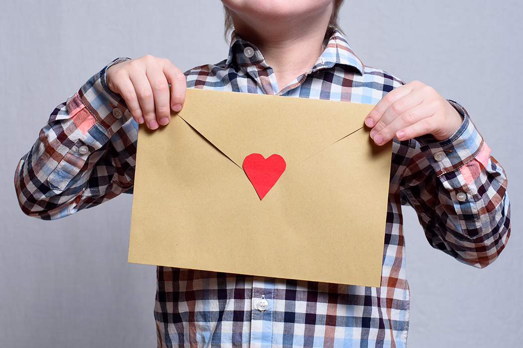 Large envelope with a red heart in children’s hands. Close-up Ways to Give Donate By Mail